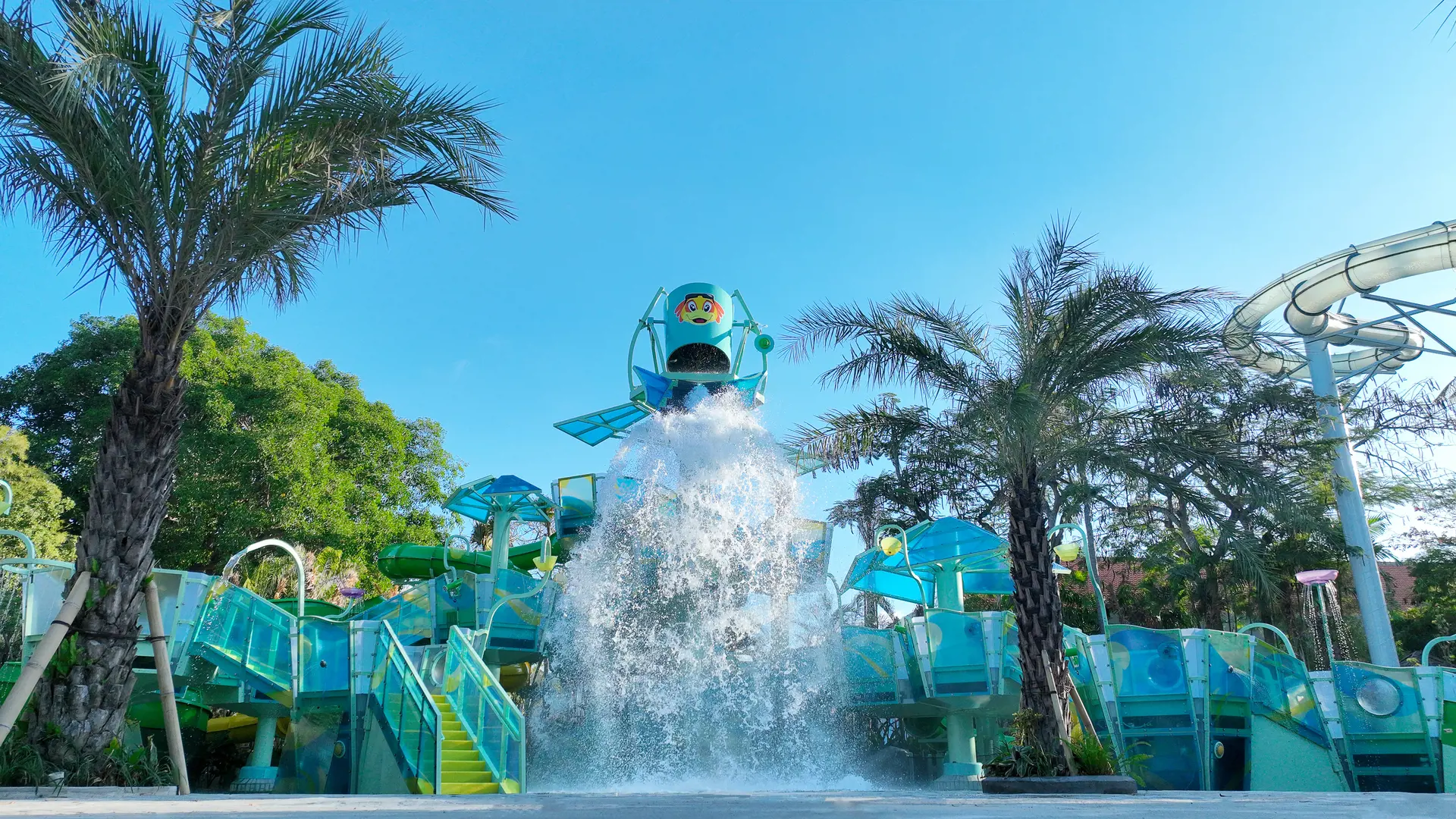 AquaPlay water tower tipping over kids play area framed by palm trees at Waterbom Bali