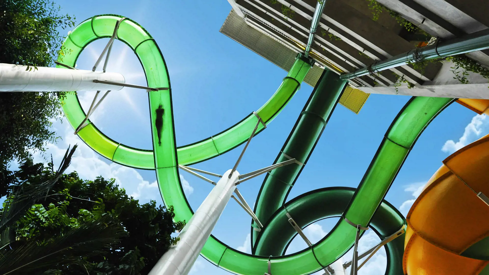 Looping green water slides twisting against a blue sky at Waterbom Bali